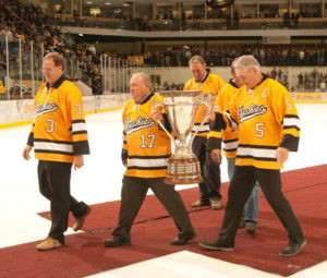 Members of the 1975 National Championship Team escort the MacNaughton Cup off the ice - MTU Image